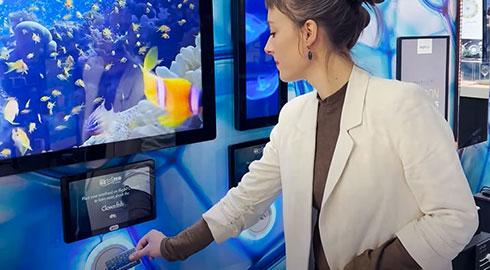 woman scanning an rfid card at an interactive museum exhibit showing various clownfish