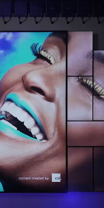 Videowall en mosaico que muestra a una mujer sonriendo con fondo azul brillante a través de varias pantallas alimentadas por BrightSign