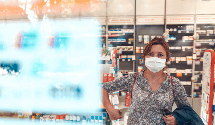 Frau mit Maske in einem Einzelhandelsgeschäft, die sich eine Auslage ansieht