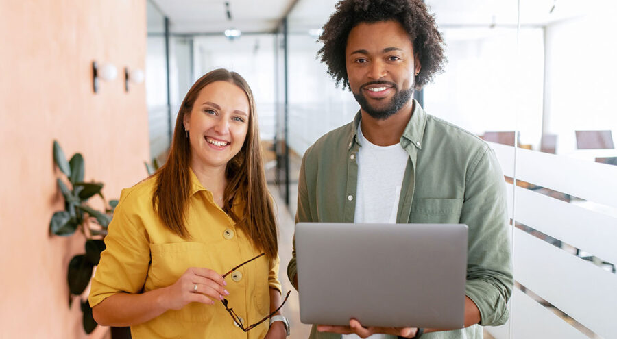 Vrouw in geel overhemd met bril naast man in groen overhemd met laptop MacBook
