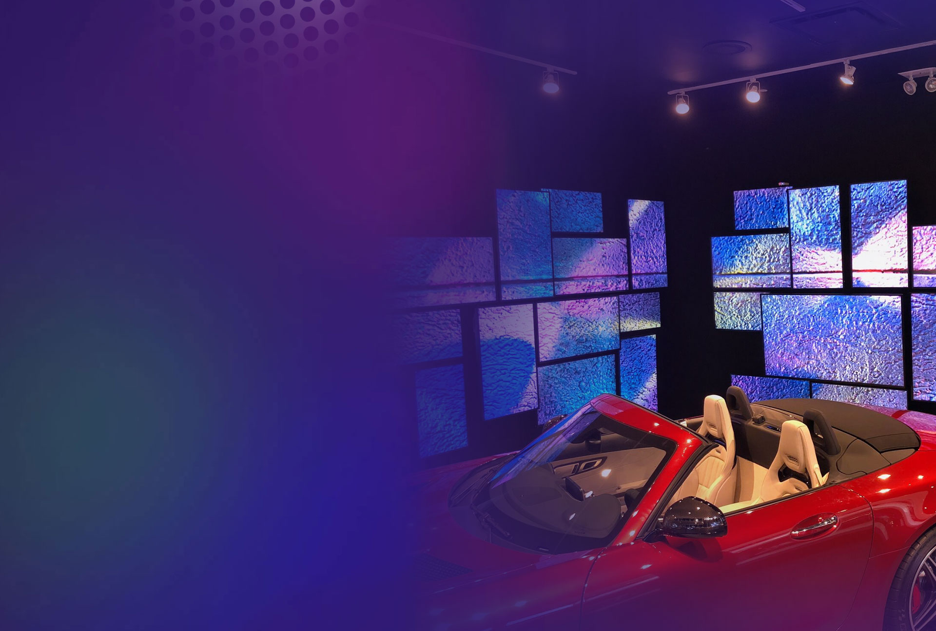 Meerdere BrightSign-gepaarde schermen met kleurrijke texturen naast rode cabrio