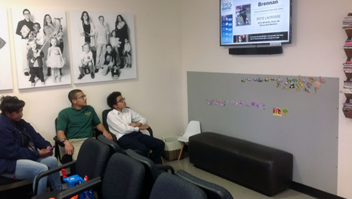een gezin bekijkt digital signage op de muur terwijl ze in de wachtkamer zitten