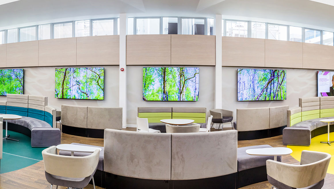 Vestíbulo de edificio sanitario con mobiliario diverso y pantallas en la pared alimentadas por BrightSign
