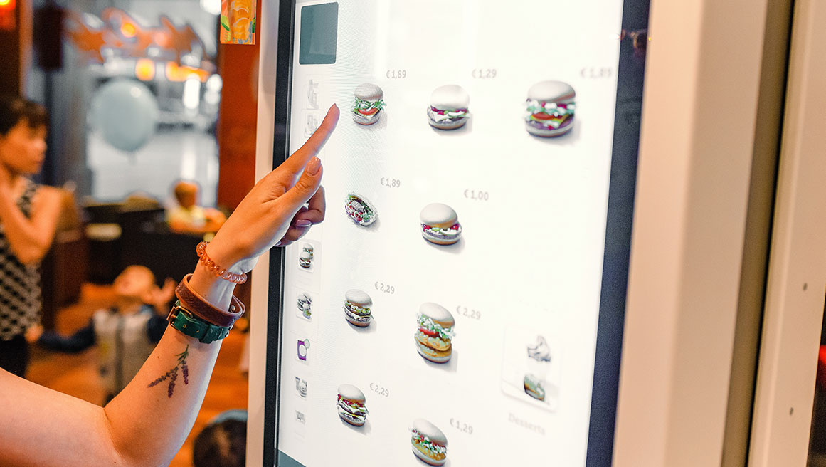 Person, die einen europäischen Touchscreen mit BrightSign-Technologie zur Essensbestellung verwendet