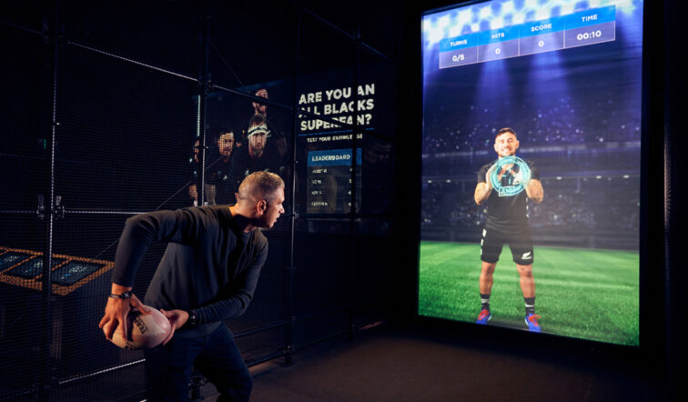 Un homme lance un ballon de rugby dans un écran interactif lors de l'expérience des All Blacks alimentée par des lecteurs d'affichage dynamique BrightSign.