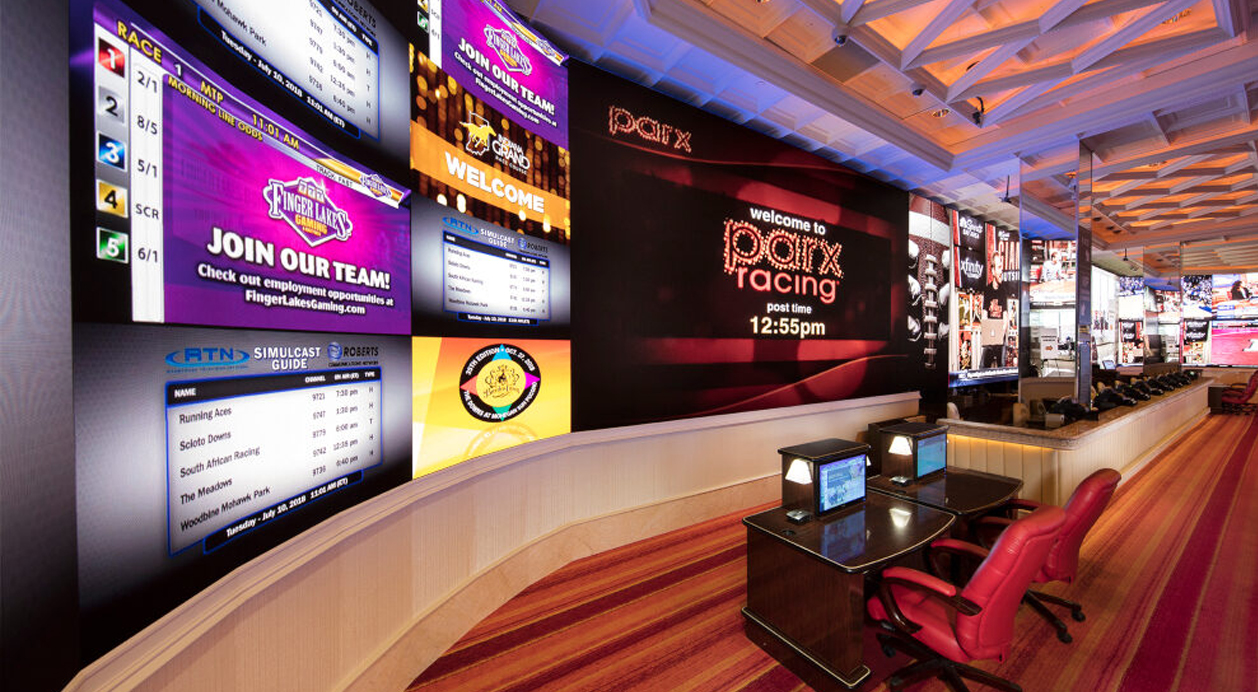 Multi-screen video wall at a casino showing live sports, promotions, and information