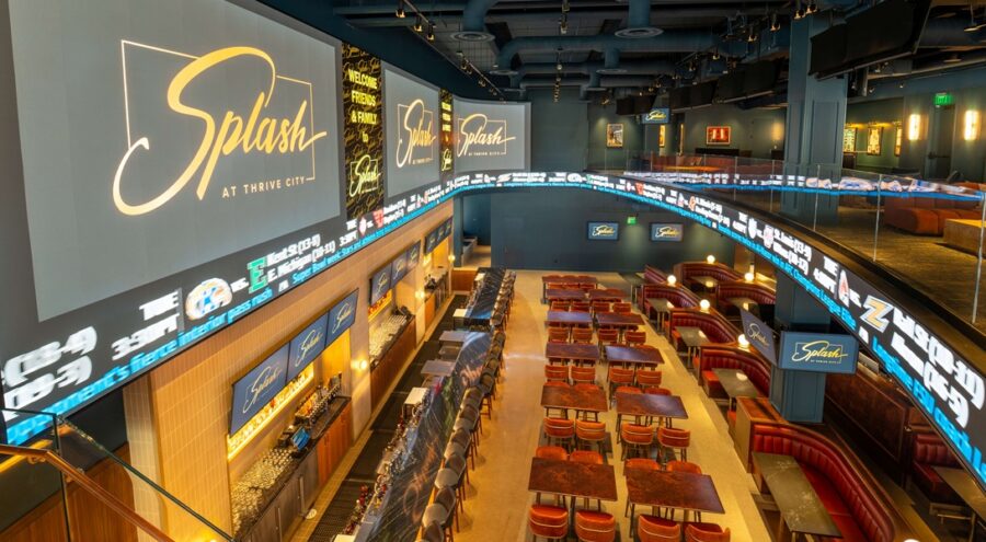 Wide shot from the second level of the dining area of Splash sports bar and restaurant with immersive digital signage and sports tickers installed around the room's perimeter